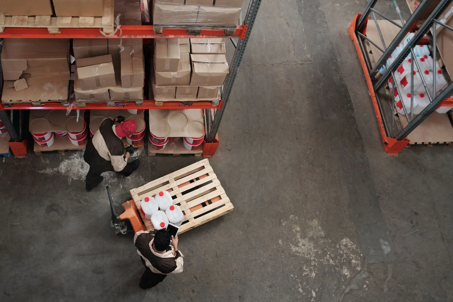 A pallet of containers on a hand truck in a warehouse aisle, seen from above